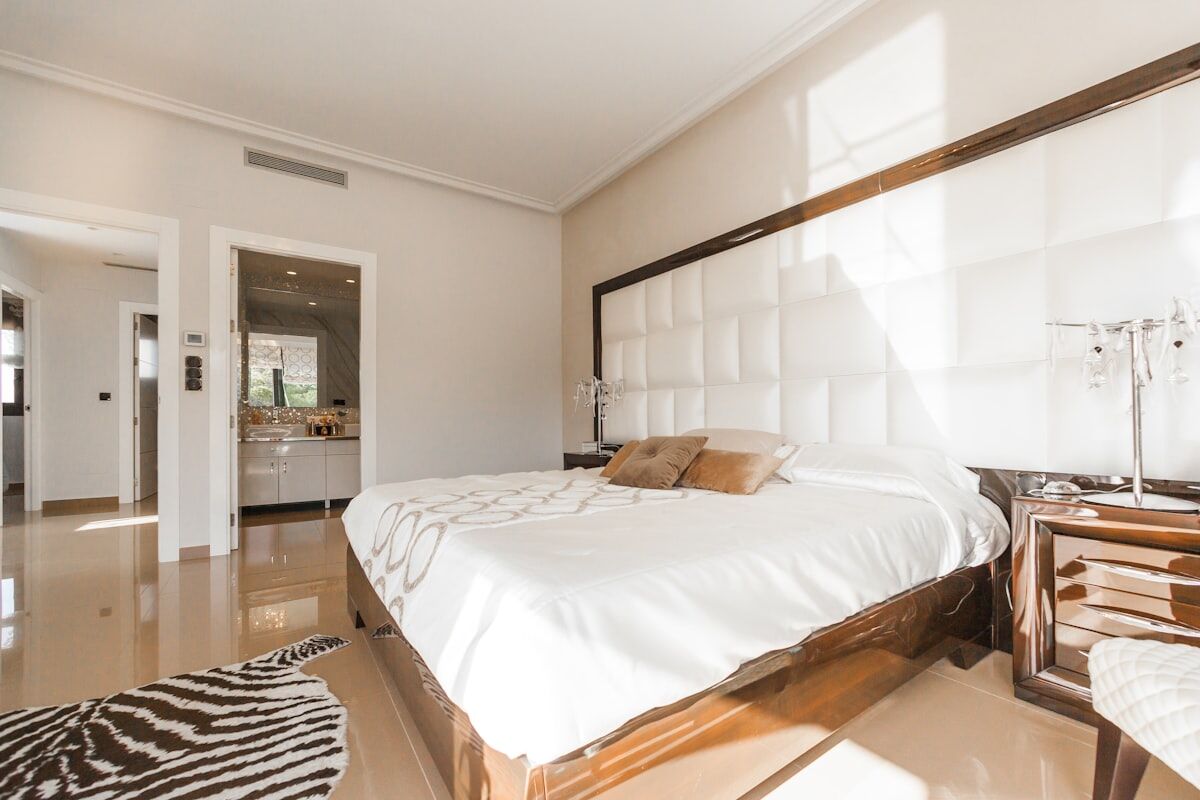 Hotel-style bedroom with a white upholstered bed and crisp linens